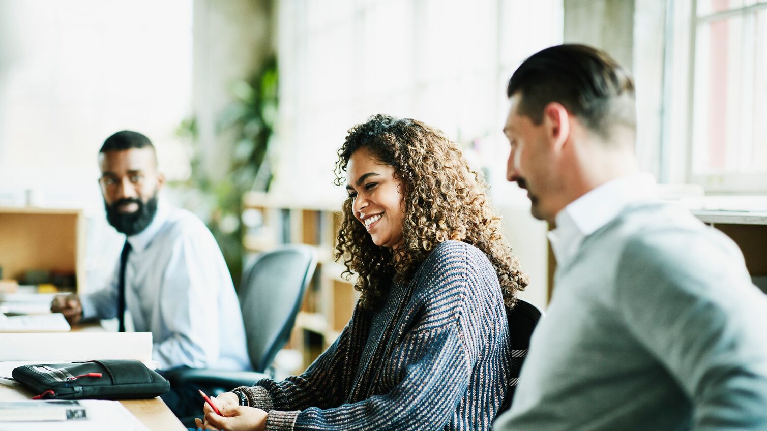 Laughing coworkers in discussion at workstation in office