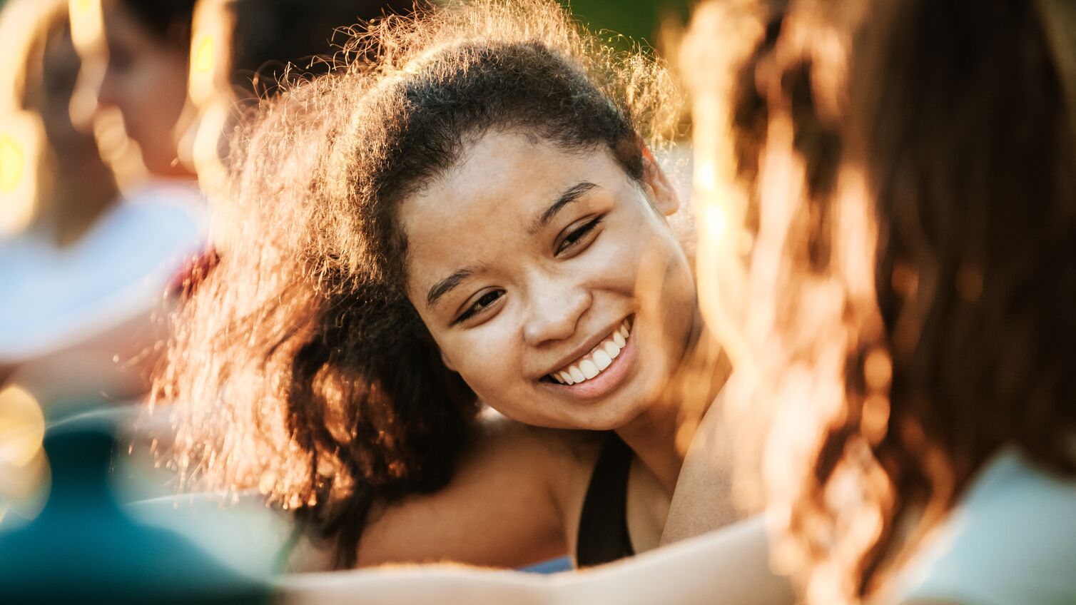 A young woman smiling while out with her fitness group, warming up before a run.