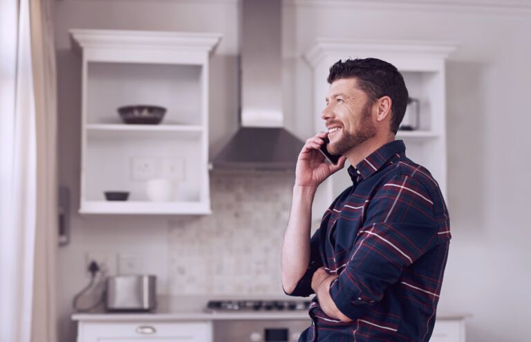 Man speaking on his mobile phone while standing in his kitchen