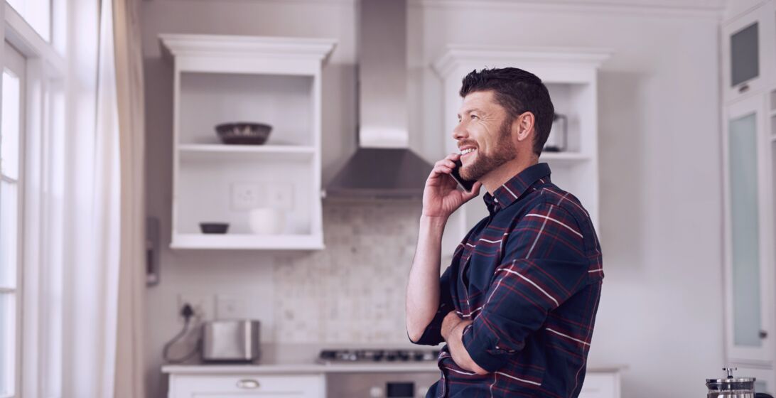 Man speaking on his mobile phone while standing in his kitchen