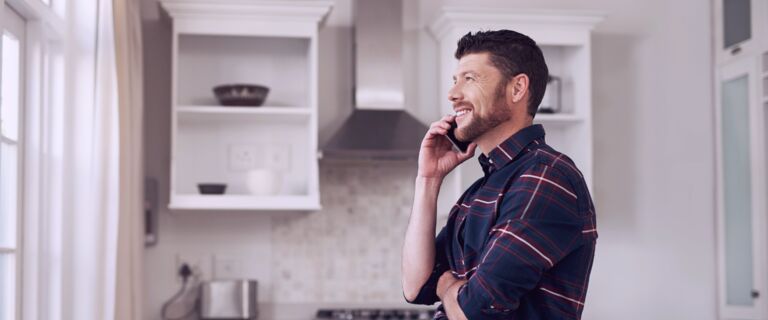 Man speaking on his mobile phone while standing in his kitchen