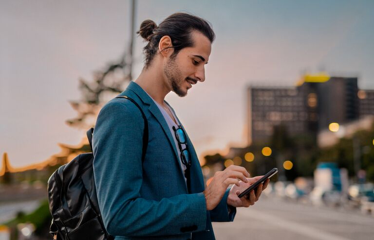 Bearded businessman working and texting on cellphone in city