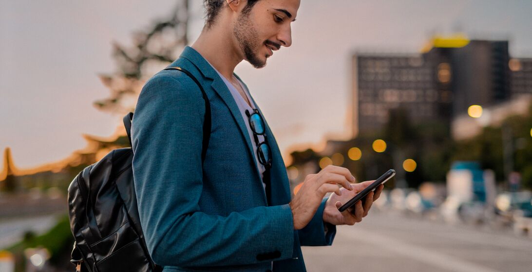 Bearded businessman working and texting on cellphone in city