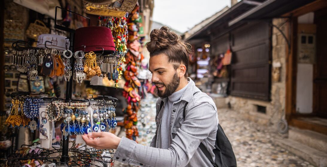 Young male tourist with backpack looking for souvenirs in local street market