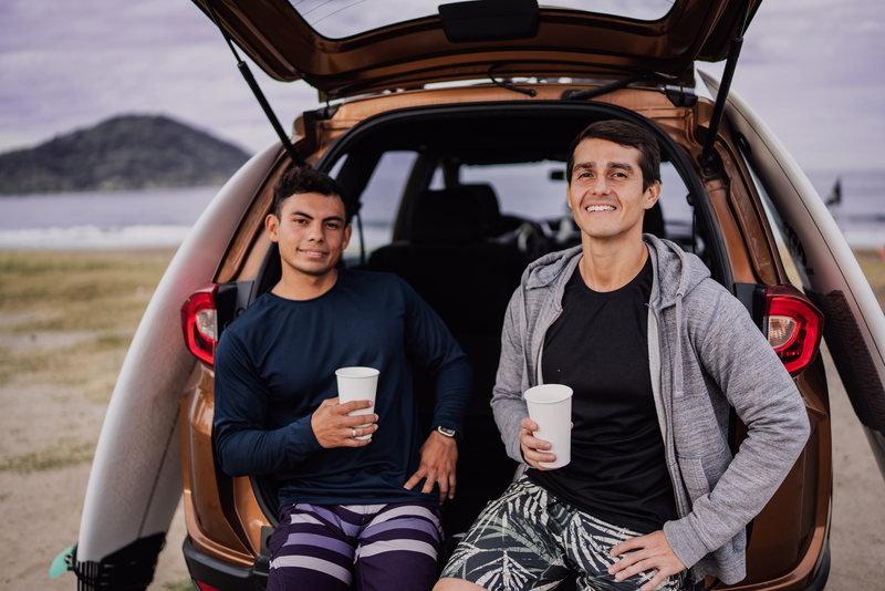 Friends sitting on car trunk at the beach?