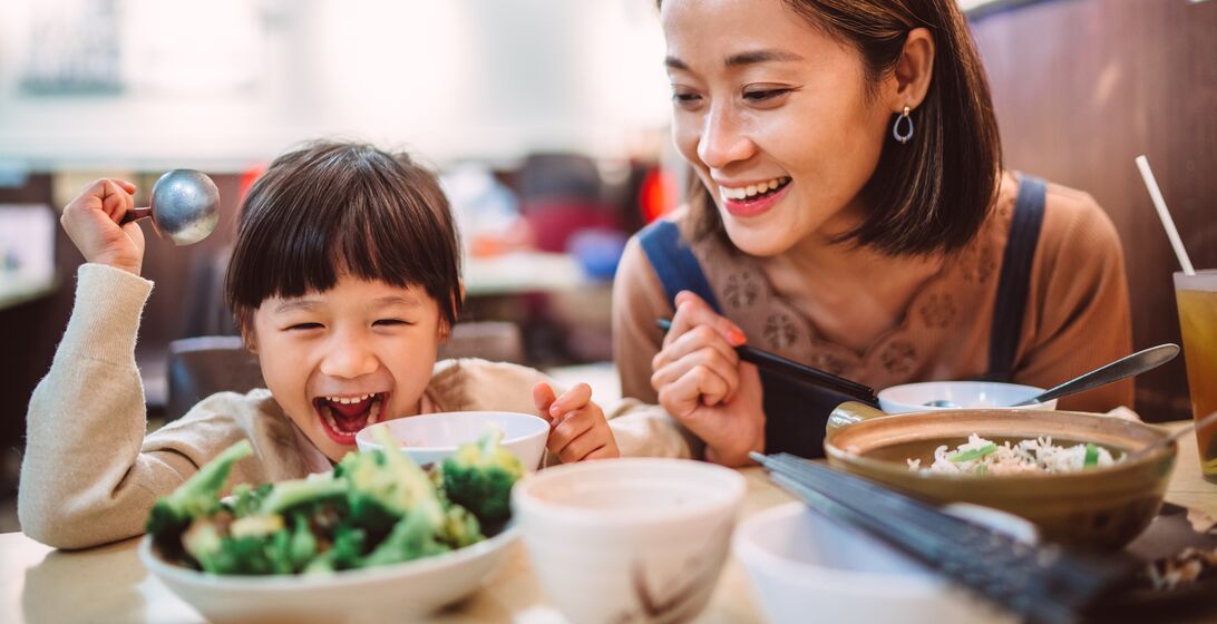 Pretty young mom enjoying meal with her lovely little daughter in the restaurant joyfully.