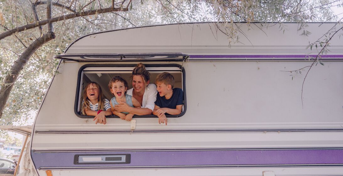 Photo of smiling mother and her children in their camper van during vacation