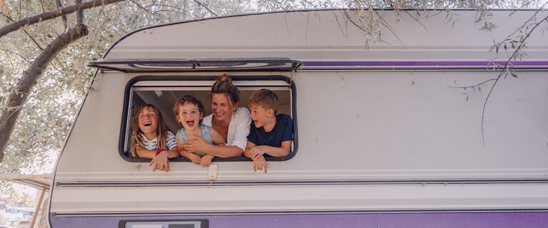 Photo of smiling mother and her children in their camper van during vacation