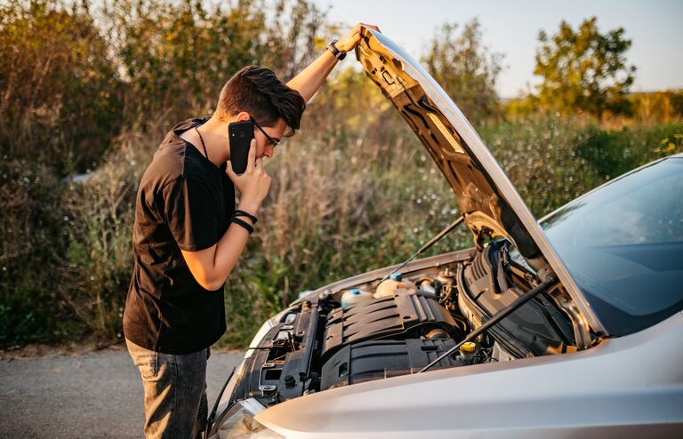 Young handsome Caucasian man had a car breakdown and calling roadside assistance.