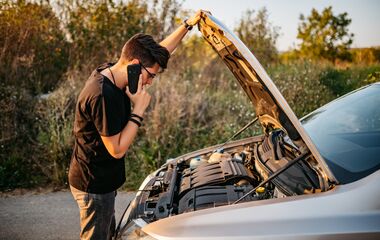 Young handsome Caucasian man had a car breakdown and calling roadside assistance.