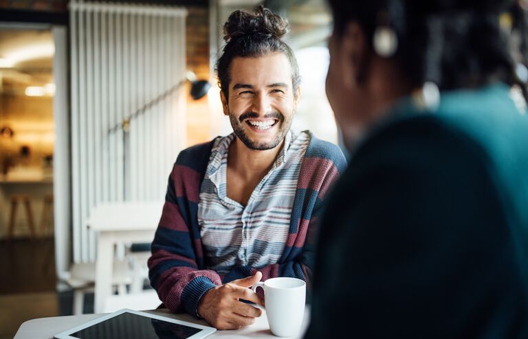 Happy businessman having coffee with female colleague while siting at office cafeteria