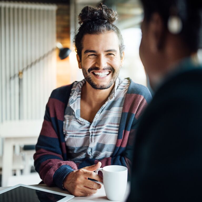 Happy businessman having coffee with female colleague while siting at office cafeteria