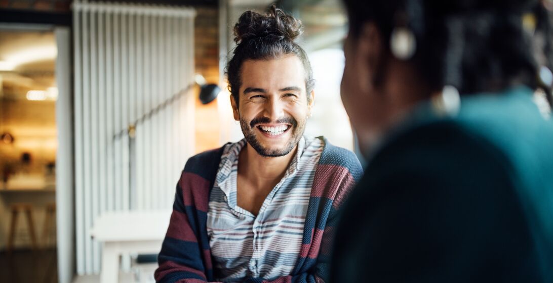 Happy businessman having coffee with female colleague while siting at office cafeteria