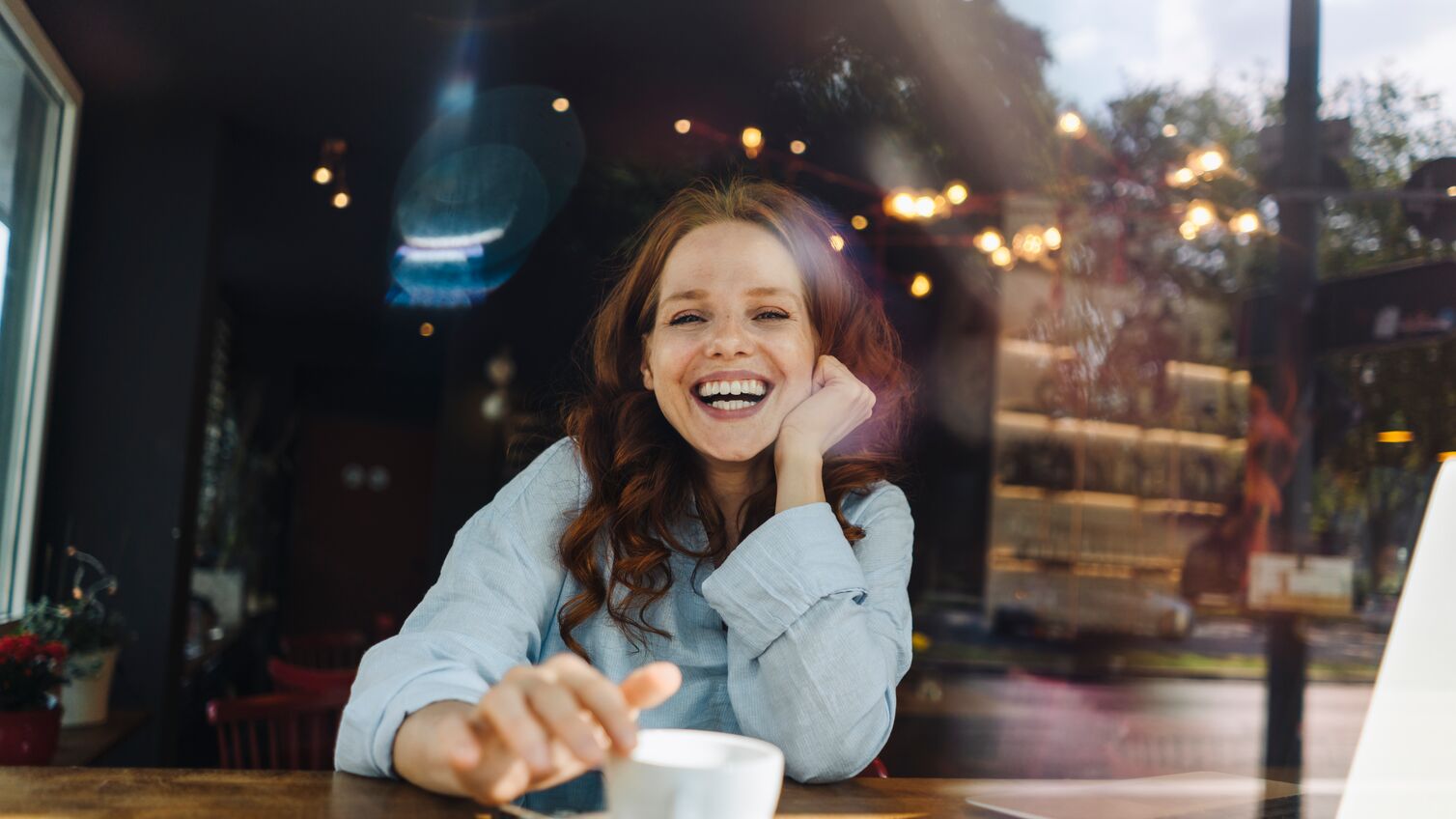 Portrait of happy redheaded woman with laptop in a cafe