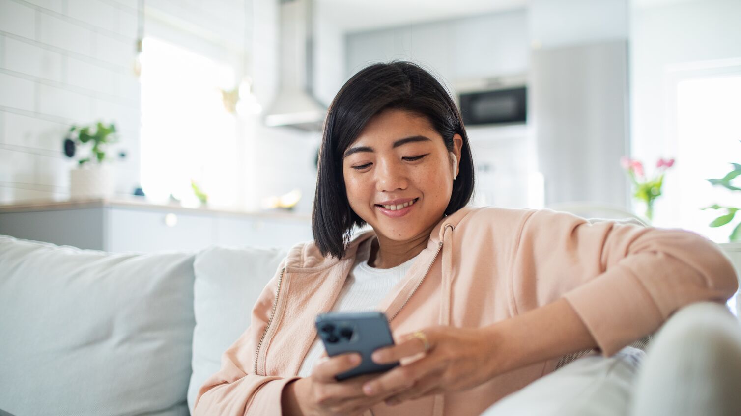 Close up of a Young woman using a smart phone while sitting on a couch in a living room