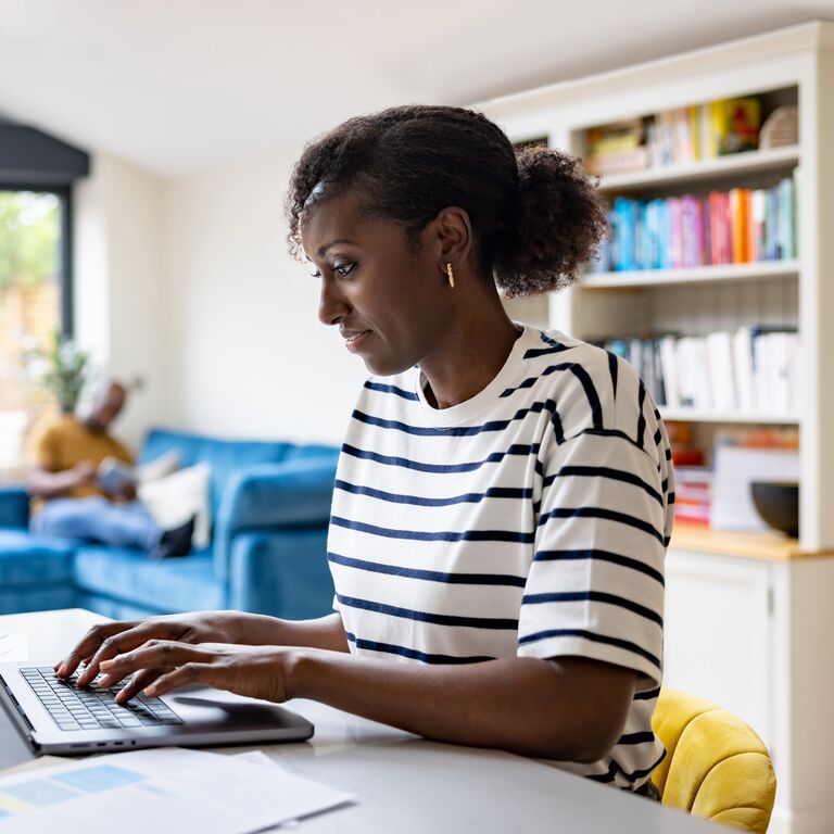 Happy black woman working at home using her laptop computer - telecommuting concepts
