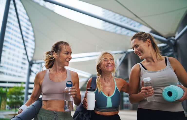 A group of young and old women walking after exercise outdoors in city, talking.