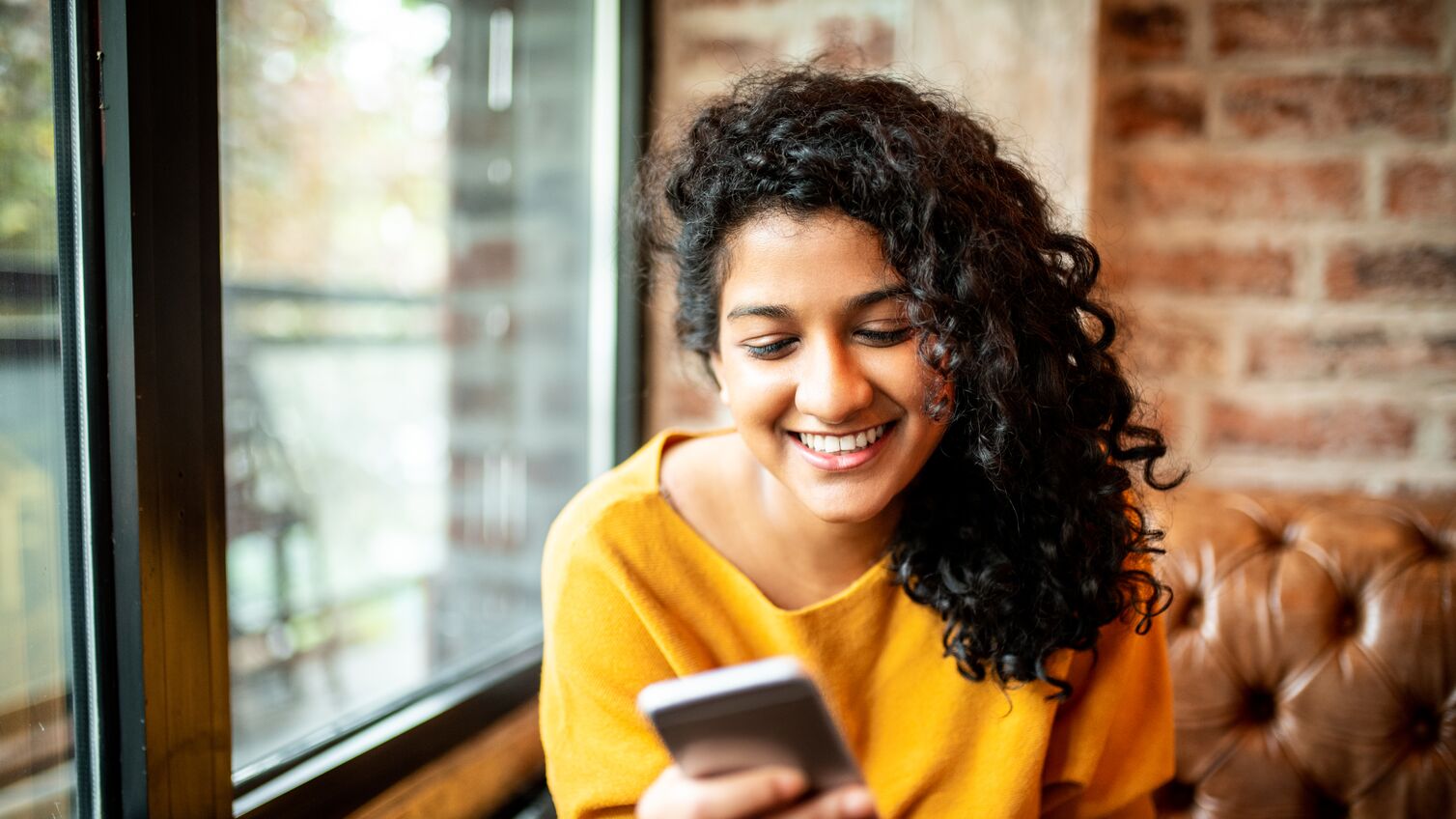 Young Indian woman using mobile phone at the bar