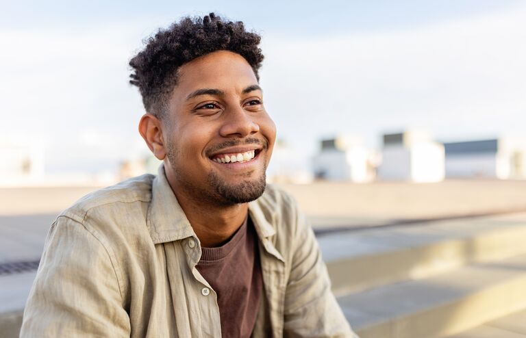 Portrait of young smiling african american man sitting outdoors. Happy people concept.