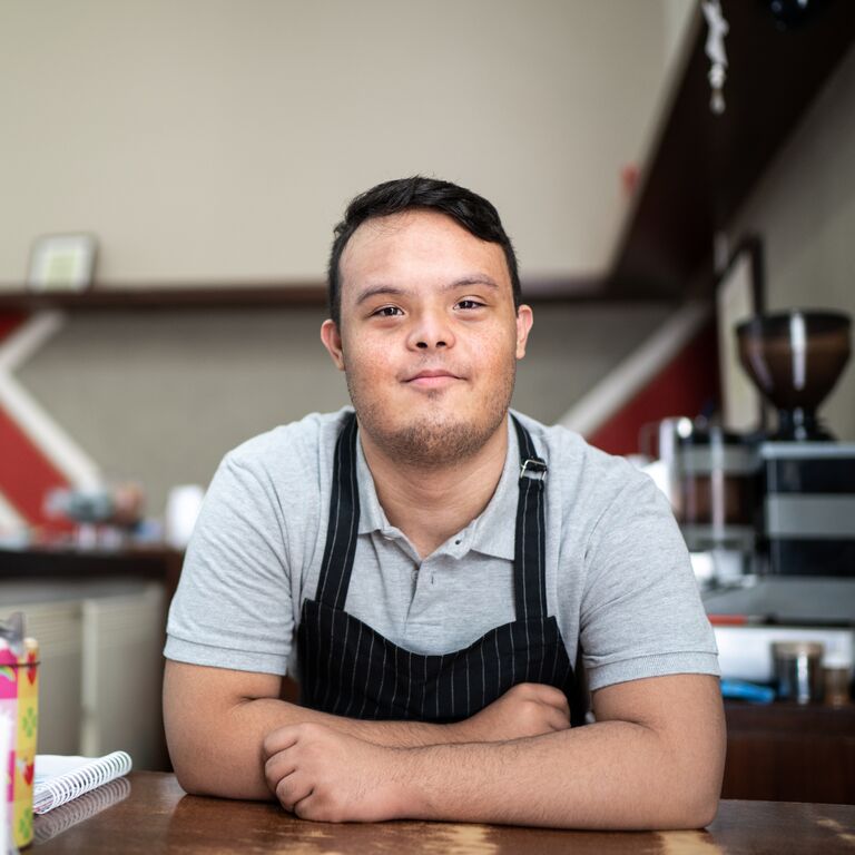 Portrait of a special need barista bending over the bar counter