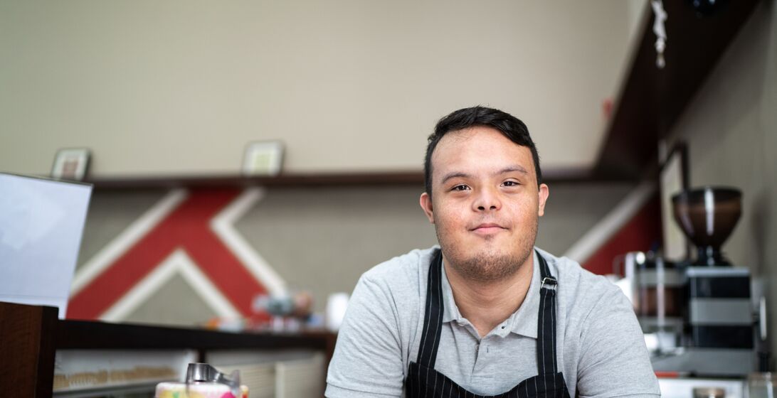 Portrait of a special need barista bending over the bar counter