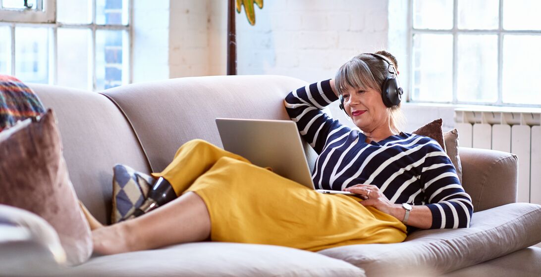 Woman in her 60s with prosthetic leg on sofa using laptop, relaxation, lifestyles, retirement